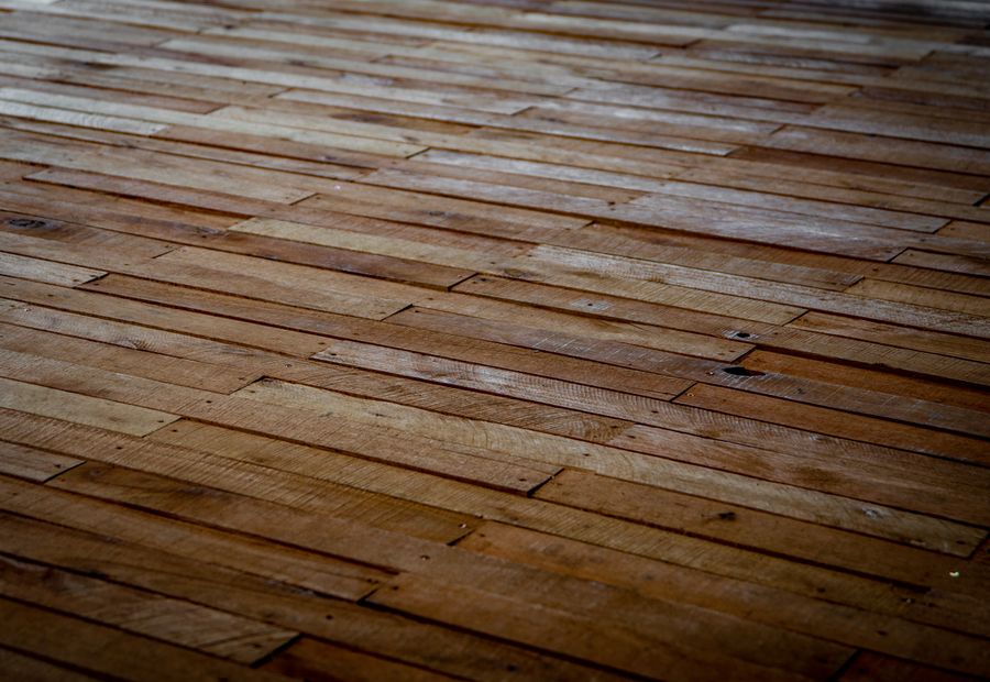 Hardwood floor mid-sanding showing bare wood and original finish